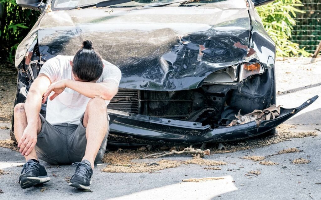 man crying on his old damaged car after crash accident 1 Cash For Used Cars Edmonton